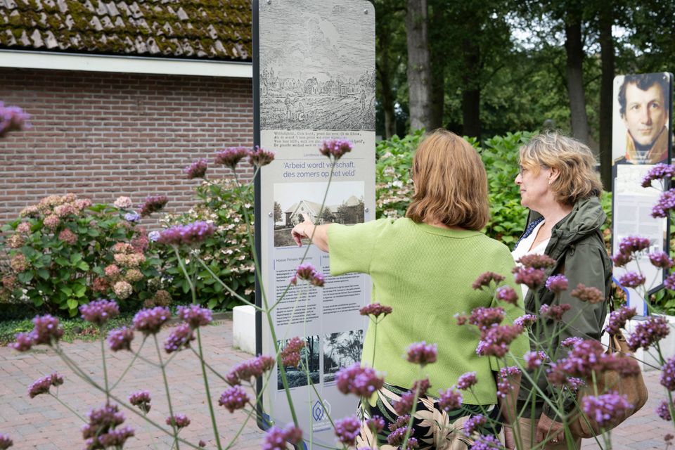 Twee dames die de buitenexpositie bij Ons Dorpshuis in Wilhelminaoord bekijken.