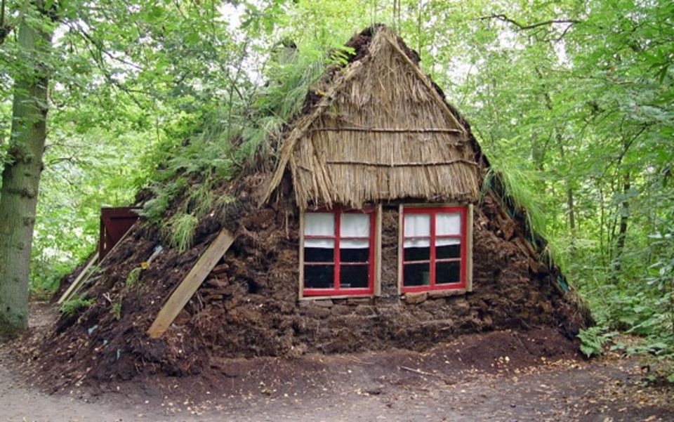 Een plaggenhut tussen de bomen.