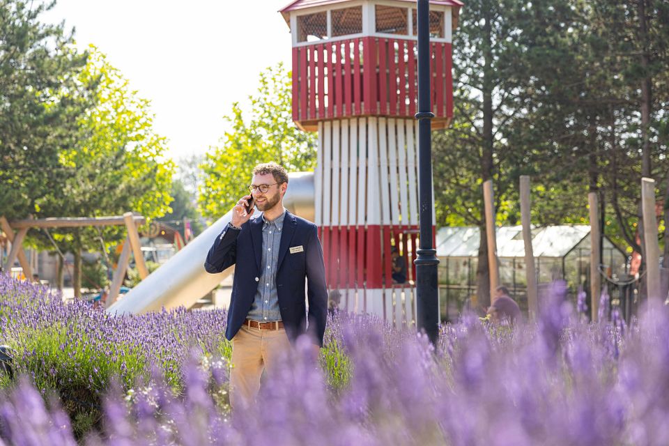 Joost belt terwijl hij achter een bloemenveld in de speeltuin van Center Parcs Port Zelande staat