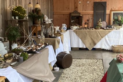 Een sfeervolle ruimte met tafels, bekleed met witte kleden en daarop diverse kerst-items tentoongesteld voor de kerstmarkt Linschoten.