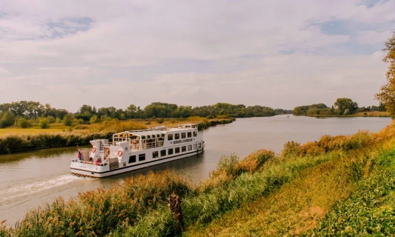 Cruiseschip vaart over de Linge in een zomers landschap