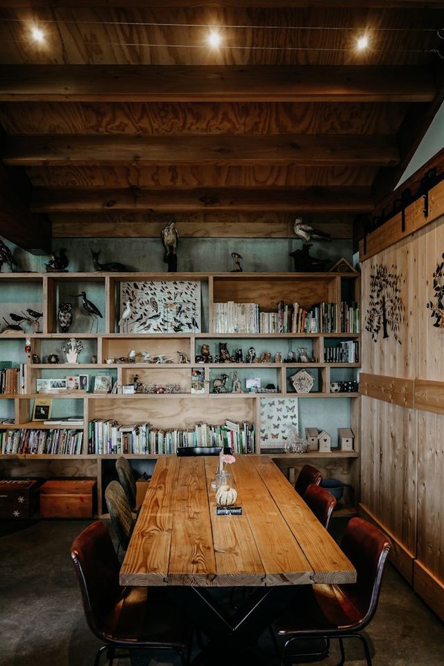 Eettafel in een hoekje met een kast vol boeken, opgezette vogels en andere vondsten uit de natuur.