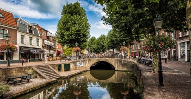 Stadscentrum Oudewater in het Groene Hart, historische binnenstad met gracht, stenen boogbrug, monumentale gevels, winkelstraat en terrassen langs het water.