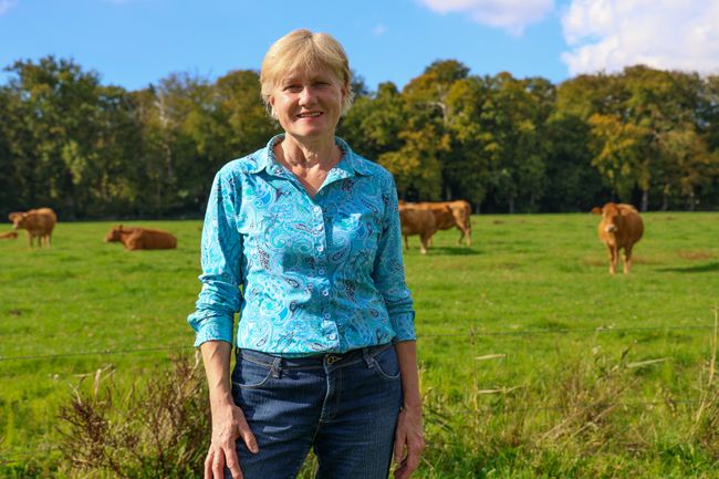 Vrouw bij een weiland met bruine koeien.