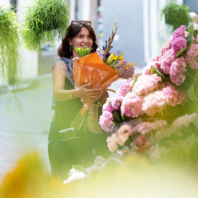 UItblinker Choe met bloemen in de hand op de markt