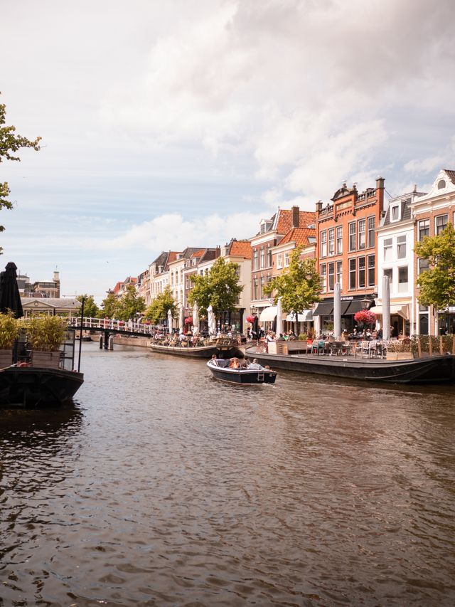 Sfeerfoto van de Nieuwe Rijn in Leiden, met terrasboten en een varende sloep op de gracht.