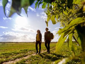 2 wandelaars in een open veld met een schijnende zon