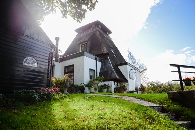Witte rietgedekte boerderij in Molenlanden met kleurrijke bloemen en groene tuin, typisch Hollands erfgoed in het Groene Hart.