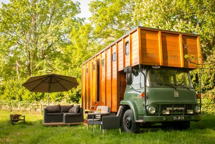 Op de foto staat het bedford te zien met de Tiny house buiten staat een lounge set