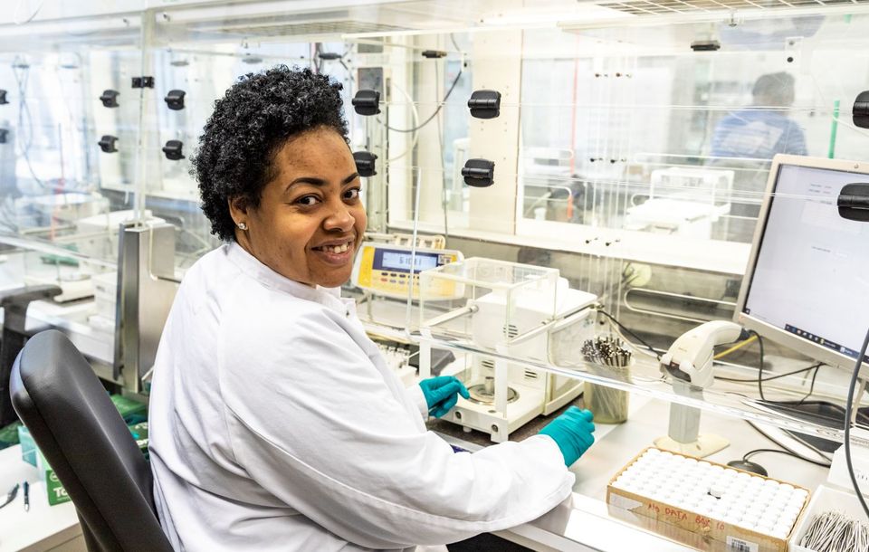 Foto van een medewerker van Specs Zoetermeer. Ze lacht op de foto en heeft voor zich allemaal spullen waar mee ze werkt.