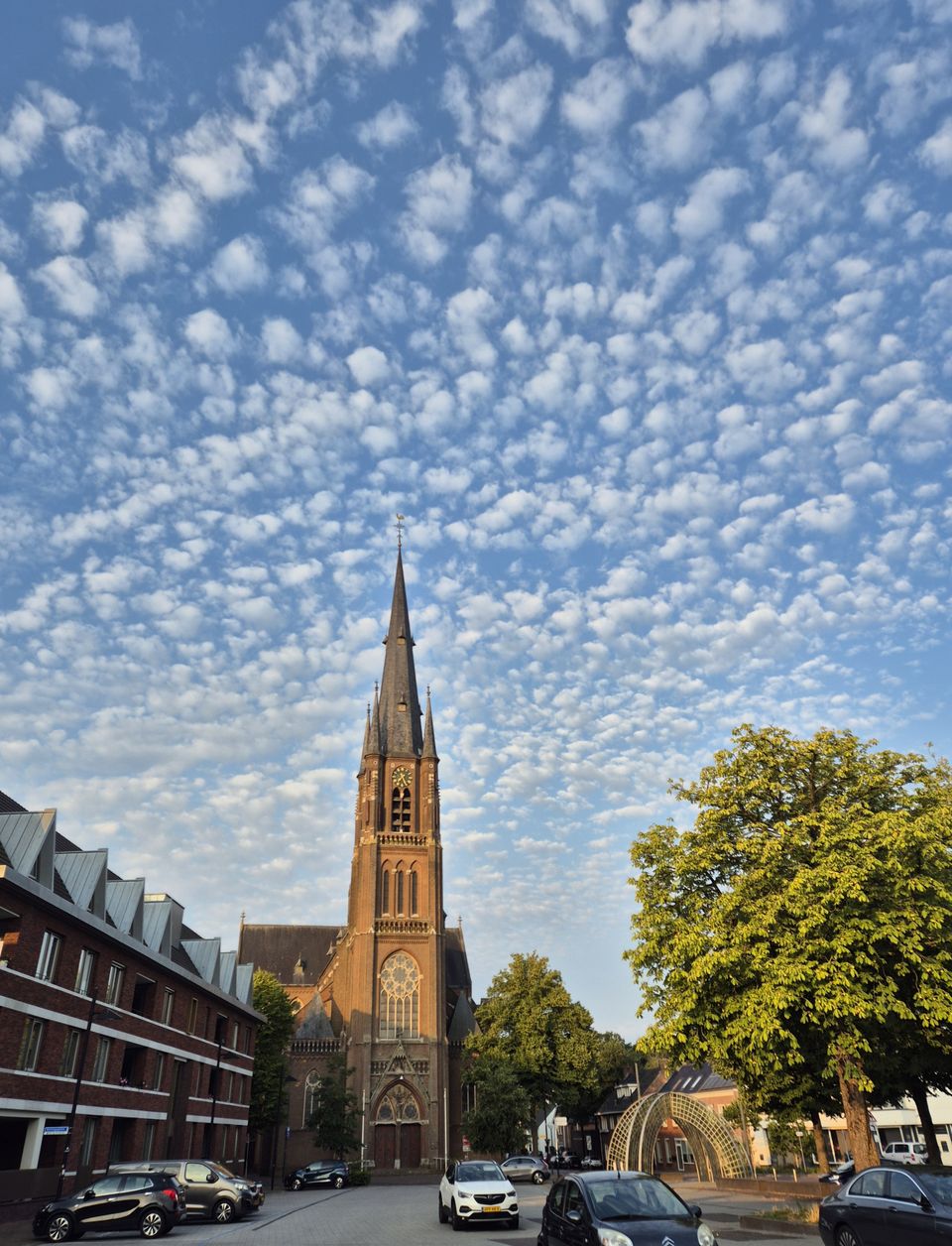 kerk vanaf het plein gezien met een blauwe lucht vol met kleine witte wolkjes