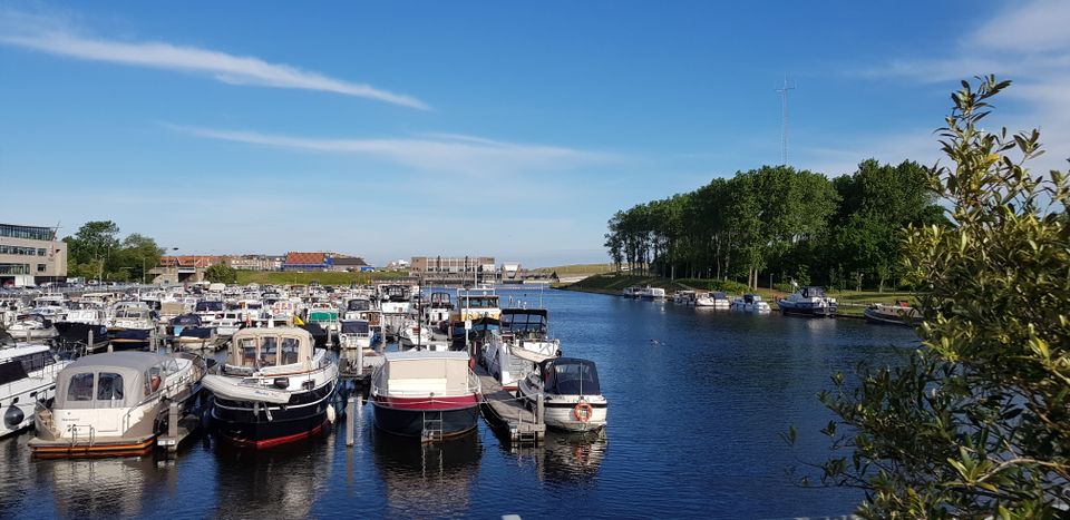 Overzichtsfoto van de Jachthaven in Katwijk met vele boten, vaarwater en op de achtergrond het Uitwateringskanaal van de Oude Rijn.