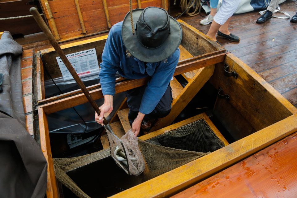 Een man zit in een boot en is bezig met een visnet
