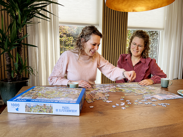 Twee vrouwen puzzelen aan tafel de Elfstedentocht puzzel van Waterland van Friesland