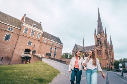 Historische bezienswaardigheden Kasteel Woerden en Bonaventurakerk in Woerden, Groene Hart, met twee wandelende bezoekers voor het kasteel en de karakteristieke kerktoren.