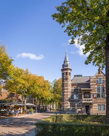Monument het Oude Raadhuis op De Lind in Oisterwijk in het herfstzonnetje. Op de voorgrond is een terras te zien.