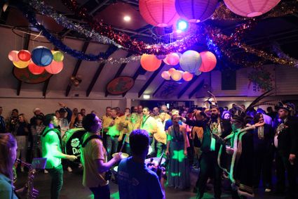 Carnavalsevenement Kleintje Carnaval in Ons Dezibel, Harmelen, Groene Hart, feestende bezoekers en brassbands in kleurrijke zaal met muziek, verklede carnavalvierders en lampionnen tijdens gratis carnavalsmiddag.