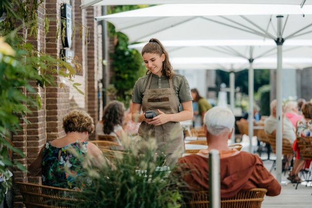 Mensen worden bedient op het terras van LIZ restobar tussen het groen