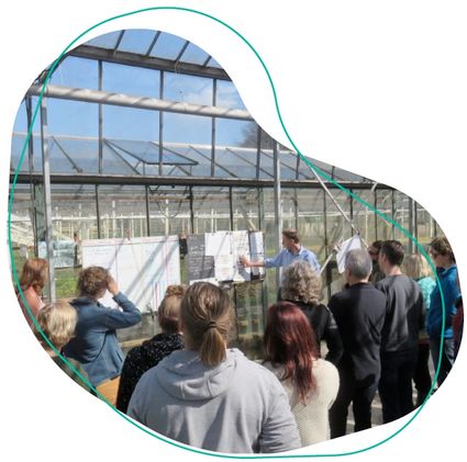 Groep personen die uitleg krijgen bij een tuinkas.