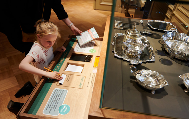 Een kind bij een la met opdrachten over het museum