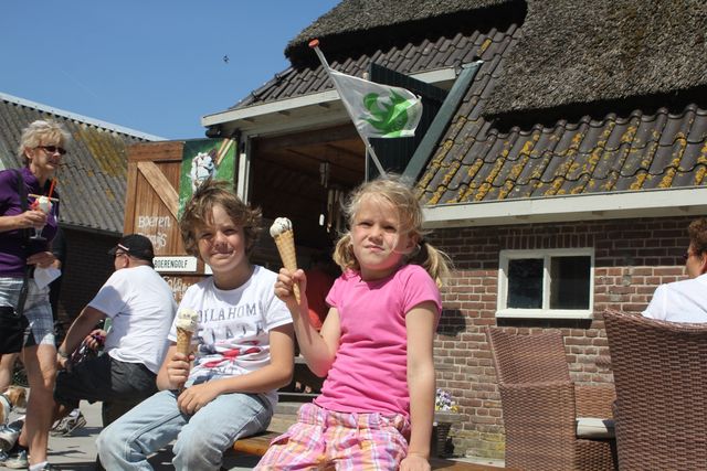 Twee kindjes op een bankje eten een ijsje bij IJsboerderij De Bûterkamp.