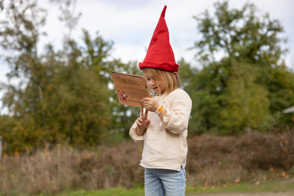 Een meisje met een rode puntmuts op is kabouterspeurtocht.