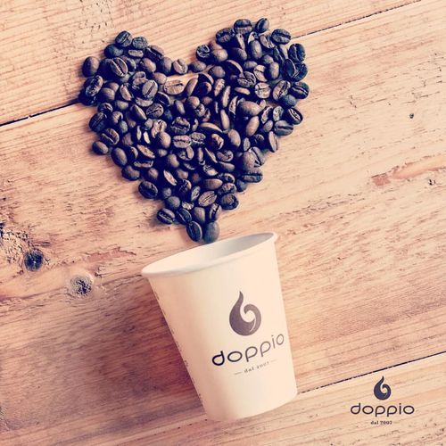 Koffiebonen die uit een koffiebeker liggen in de vorm van een hartje