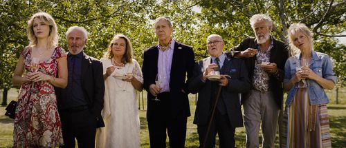 Een groep mensen in nette kleding met taart en champagne