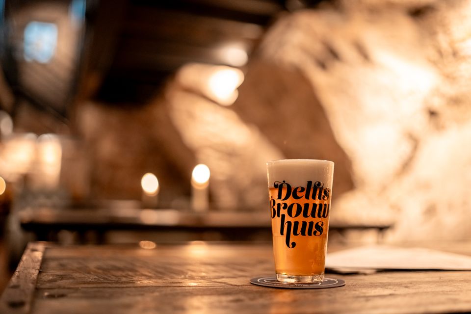 Een glas bier op een tafel in Delfts Brouwhuis met een vervaagde achtergrond