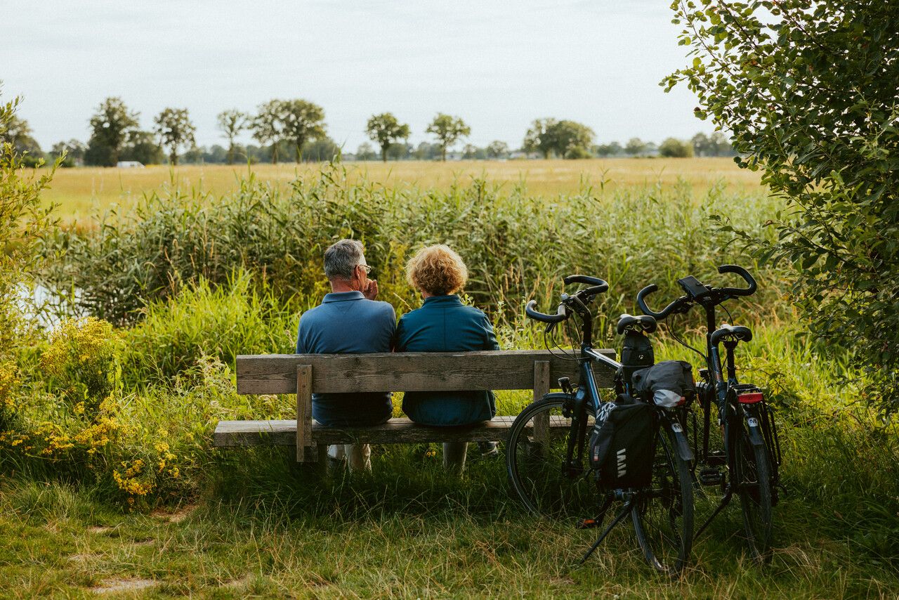 Achteraanzicht twee mensen op een bankje, fietsen ernaast.