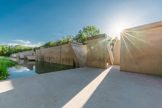 Grote betonnen panelen die soms dwars staan. De oorspronkelijke functie van deze was een Deltagoot. Dit staat in het Waterloopbos in de Noordoostpolder.