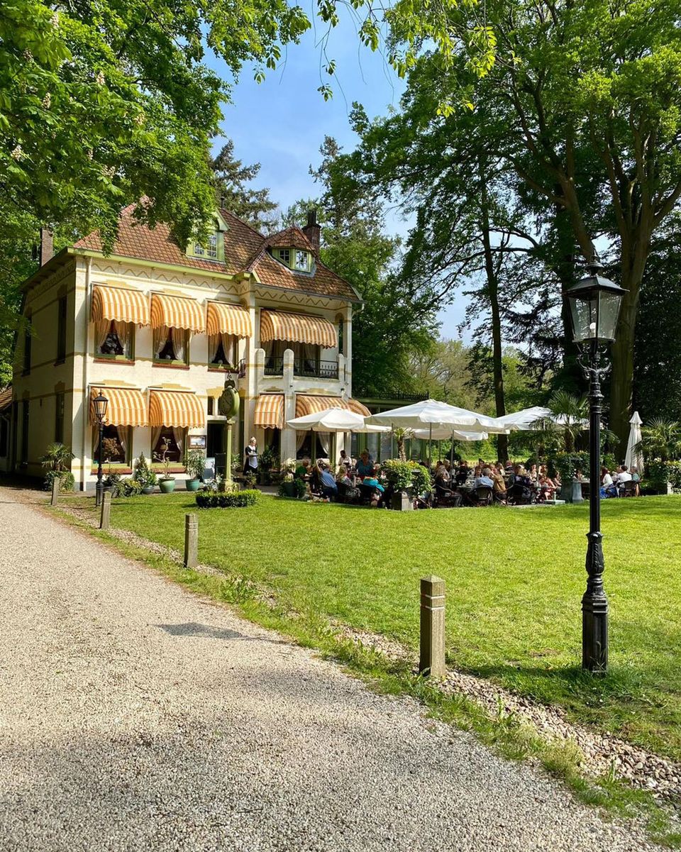 Het statige witte pand en het gezellige terras in de groene omgeving van Tea Time in Echten.