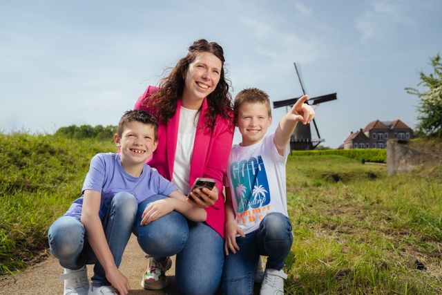 Moeder met twee kinderen speelt de webapp Ontdek Willemstad rondom de vesting met een molen op de achtergrond
