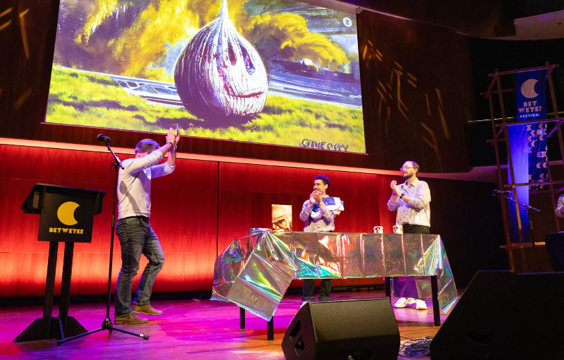 Drie mensen dansen en klappen op een podium