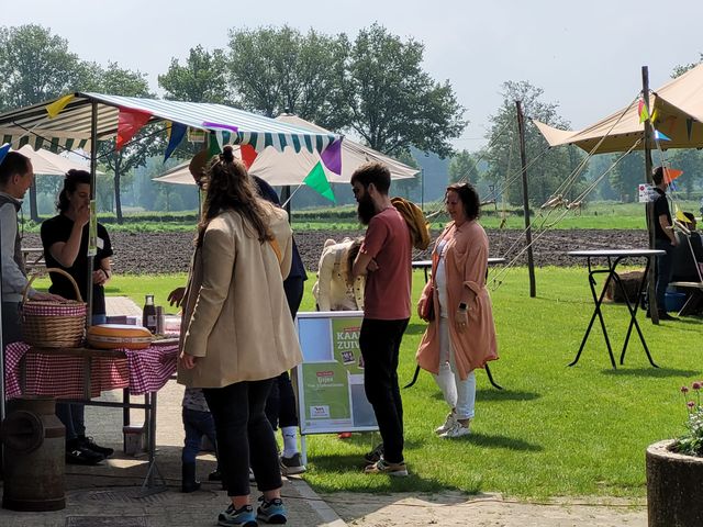 Groepje mensen bij een kraam op de wei van Koeientuin Tierelier