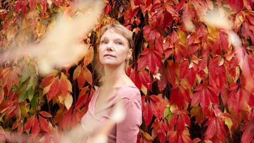 Laura van Dolron in een bos vol met rode bladeren