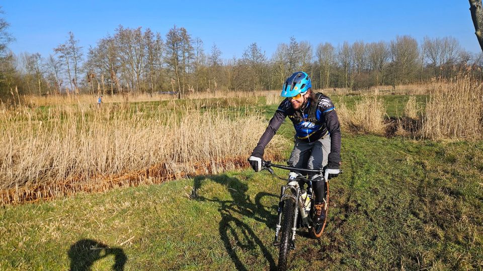 een mountainbiker fietst in het veld, gekleed in TWC outfit