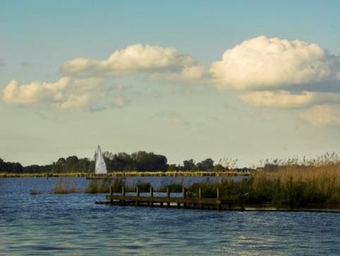Het Leekstermeer met een zeilbootje op de achtergrond.