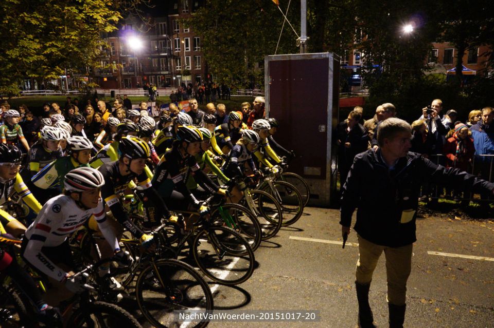 Wielersportevenement Nacht van Woerden in Woerden, Groene Hart. Start van een cyclocrosswedstrijd in de avond met wielrenners aan de startlijn, publiek langs het parcours en sfeervolle verlichting in de historische binnenstad.