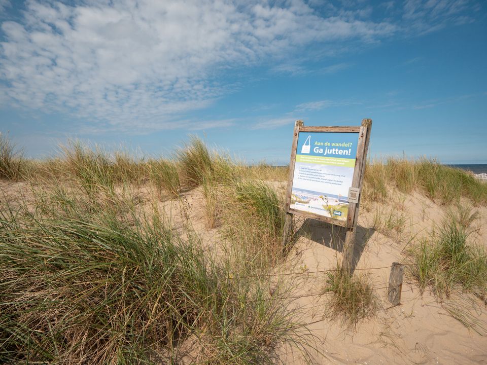 Foto van de strand met een bord en op het bord staat informatie over de schonen strand.