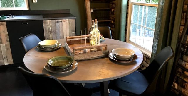 Donkere keukenfoto met ingedekte ronde tafel en keukenblok op de achtergrond.