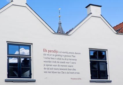wit huis met gedicht op de gevel