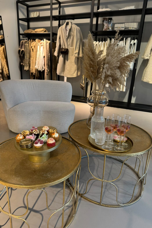 Een zithoekje met twee stoelen en rond tafeltje in een kledingwinkel.