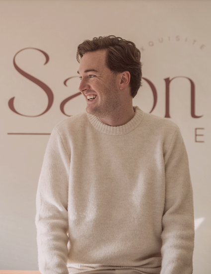Freek van Remunt staat voor een wand in zijn salon met de naam Salon Frere