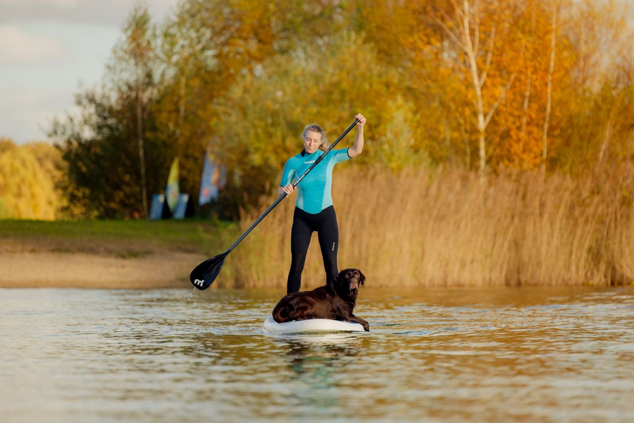 vrouw suppend met hond liggend op de plank.