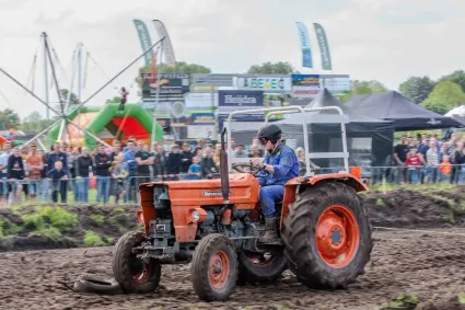 Evenement Boerendag, Oudewater, Groene Hart, trekker behendigheidswedstrijd met bestuurder op modderig parcours en publiek langs de kant tijdens agrarisch familie-uitje.