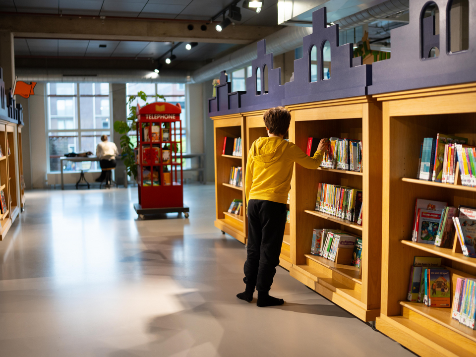 Een jongen in de bibliotheek van Delft zoekend naar een boek