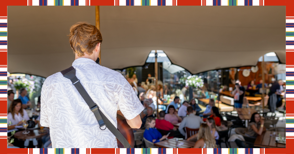 Een man die aan het optreden is en mensen die op het terras zitten