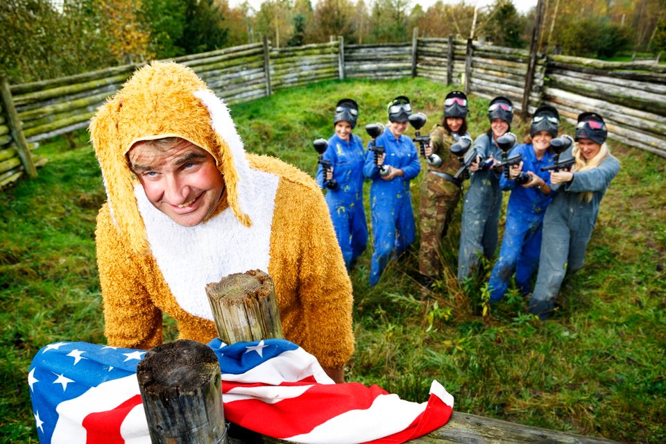 Man in hazenpak wordt onder schot genomen door mensen met paintballgeweren.