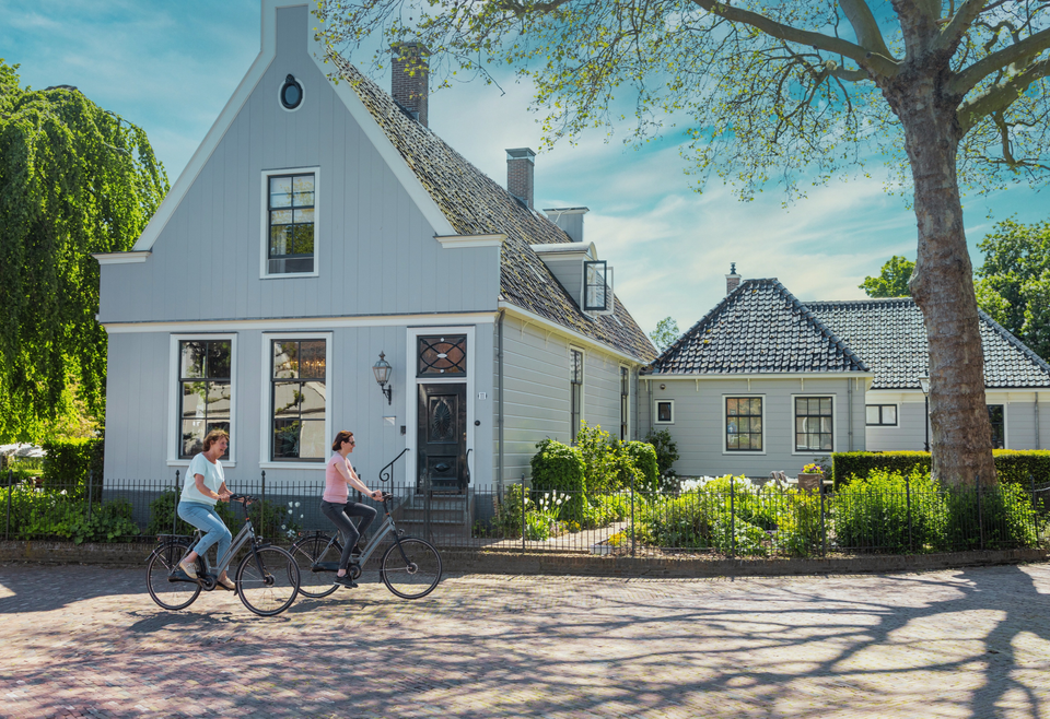 Twee vrouwen die op een zonnige dag fietsen door Broek in Waterland
